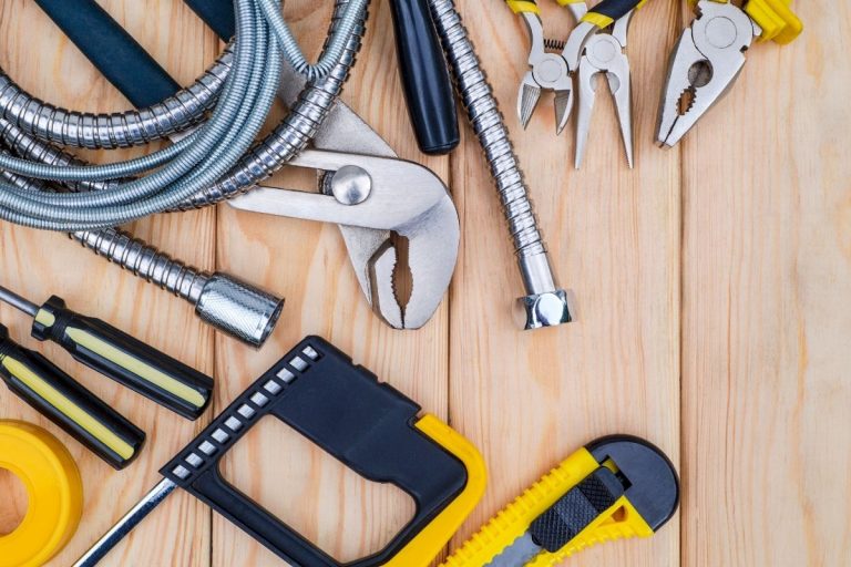 An assortment of tools, such as hammers and saws, laid out on a wooden table, showcasing a workspace ready for projects.