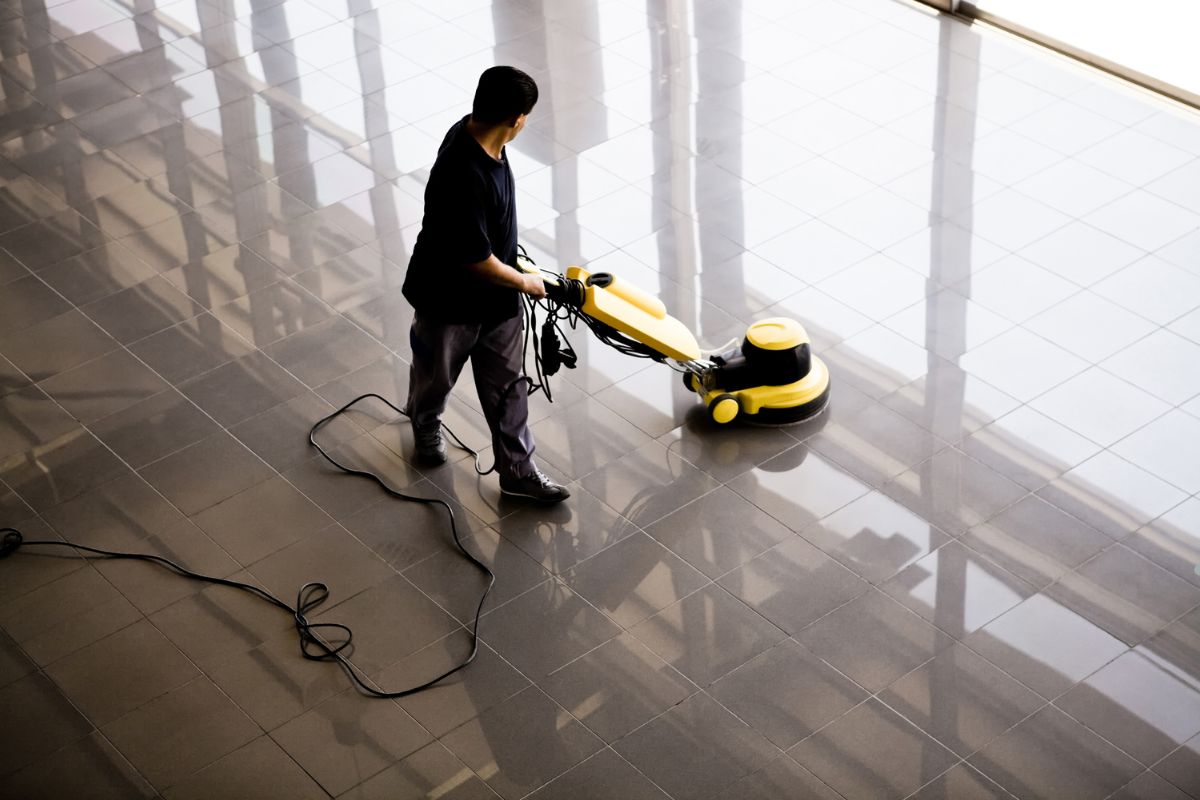 A man using a vacuum cleaner to clean a floor, showcasing heavy-duty scrubbers for effective cleaning.