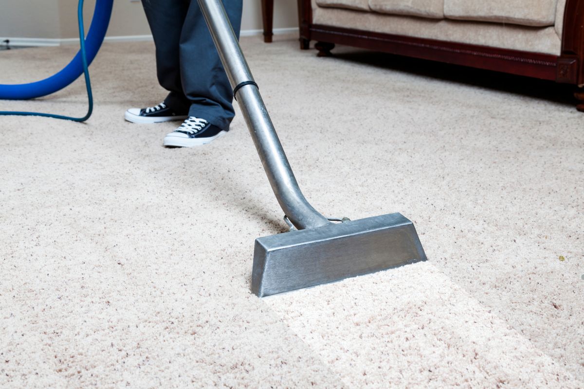 A person vacuuming a carpet, demonstrating a DIY cleaning solution for home maintenance.